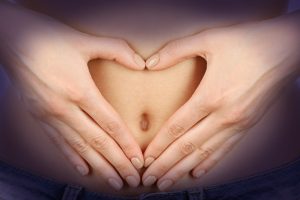 loving hands form a heart around the navel