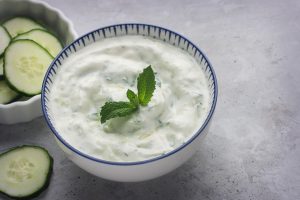 cucumber yoghurt salad with cucumber slices and a mint leaf on top