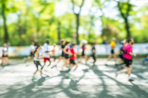 People running down a road shaded by trees - blurry image