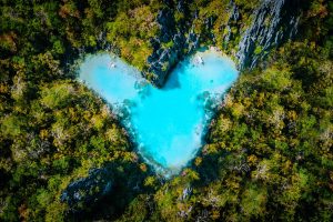 heart shaped light blue lake surrounded by forest