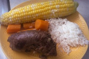 beef rolls on a plate with rice, carrots,corn