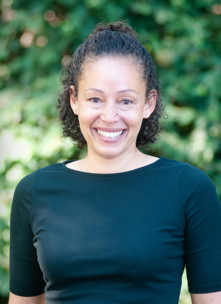 Portrait of Dr. Kimani Borland in front of a green hedge